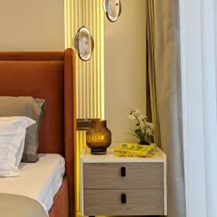 A close-up of a bedroom's accent wall, featuring a fluted panel with integrated vertical lighting that creates a warm and sophisticated ambiance.