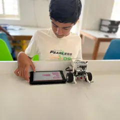 A student makes final adjustments to his code on a tablet before running his LEGO robot. This iterative process of coding, testing, and refining is fundamental to robotics.