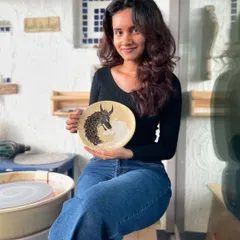 A student proudly showing off her yin and yang dragon Sgraffito plate. It's amazing to see personal symbols and intricate designs come to life in the studio.