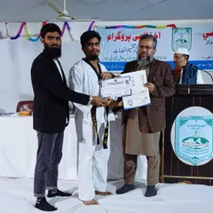 Receiving a black belt certificate is a huge honor. Here, I am presenting this achievement to a student at a ceremony at Jamia Islamia Sanabil.