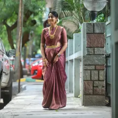 A full-length view of a graceful look for a family wedding. The makeup is kept elegant and fresh to complement her beautiful mauve silk saree and traditional gold jewelry.