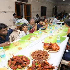 A family enjoying the full spread on a traditional banana leaf, complete with biryani, fried chicken, and various side dishes. This is what a true South Indian feast looks like.
