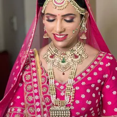 This bride looks absolutely radiant in a heavy polki and pearl layered set, complete with a matha patti and nath, perfectly complementing her bright pink lehenga.