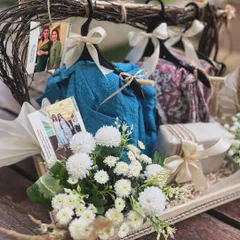 A unique "hanger hamper" styled for a fashion label's birthday gift. Miniature hangers display beautiful fabrics, surrounded by fresh white flowers and personalized photos, creating a truly bespoke and memorable present.