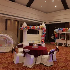 A view of the entertainment zone at a carnival party, featuring a white bouncy castle and a bubble house.