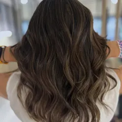 A perfect beige balayage for that summer-ready feel. The highlights are blended seamlessly for a lived-in look, styled into beach waves to show off the dimension.