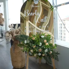 A chic welcome sign for a 'Bearly Wait' baby shower. The mirrored acrylic sign is paired with dried pampas grass and fresh flowers for a perfect boho-modern look.