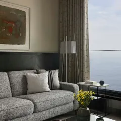 In this sea-facing apartment, the living room is a study in restraint. A simple color palette and soft textures ensure that the expansive view of the water remains the focal point, creating a calm and sophisticated urban retreat.