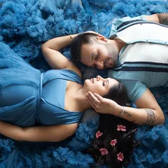 An artistic overhead shot of a couple nestled in a sea of blue fabric. This pose creates a feeling of intimacy and a dreamy, water-like effect.