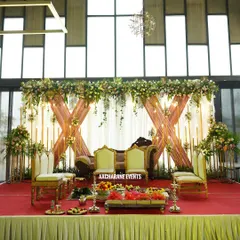 This modern reception stage combines elegant drapery with a floral arch and warm, candle-like lighting. The setup includes traditional brass lamps and seating for a perfect blend of contemporary and classic styles.