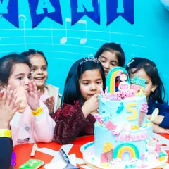 The birthday girl surrounded by friends, ready to cut her amazing rainbow and ice cream themed cake. We coordinate the entire celebration for a seamless experience.