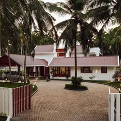 The entrance to the 'Coconut Cove' residence, where the paved driveway curves around existing palm trees. This view demonstrates how landscape planning dictates the approach and initial experience of the home, immediately establishing a harmony with nature.