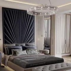 A dramatic and glamorous bedroom design centered around a tall, fan-shaped upholstered headboard in dark velvet. The crystal ring chandelier adds a layer of opulence, making this a truly statement-making personal space.