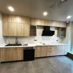 Another view of the wooden-finish kitchen, showing the ample counter space and the combination of closed cabinets and glass-front units.