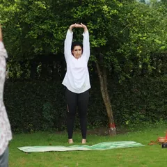 Leading the class in a standing overhead stretch to lengthen the spine and open the shoulders. Practicing under the open sky adds a special sense of freedom.