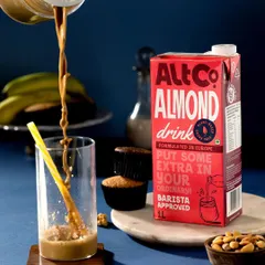 A dynamic pour shot of Alt Co. Almond Drink. The frozen motion of the liquid creates a powerful sense of action and energy, making the product look delicious and exciting.