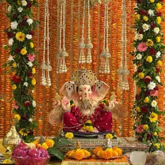 For this Ganpati stage decoration, I used a backdrop of marigold flower strings and framed it with colorful floral garlands. The pearl string hangings add a touch of elegance to the traditional setup.
