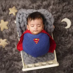 Our little superhero rests in his tiny bed, surrounded by stars. The full setup shows the creative details that go into a themed infant photoshoot.