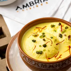 The royal Kesari Rasmalai. Soft cheese dumplings soaked in saffron-infused milk, garnished with pistachios. A timeless Indian dessert for a luxurious finish.