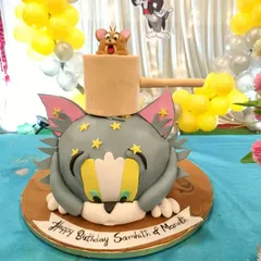 A playful and highly detailed 3D sculpted Tom and Jerry cake. This fun design captures the classic cartoon chase, with Jerry popping out of a mallet on top of Tom's head.