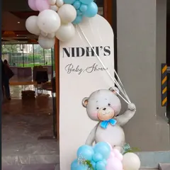 A dreamy welcome sign for a baby shower. The teddy bear theme is carried through with a cute illustration and a pastel balloon garland.