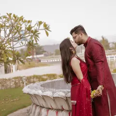 A romantic kiss in matching maroon traditional outfits. The urban background with the fountain adds a nice contrast to their ethnic attire.