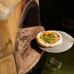 A freshly prepared vegetarian pizza on a peel, ready to enter the brick wood-fired oven. This live station brings the authentic sights, sounds, and smells of an Italian pizzeria to your event.