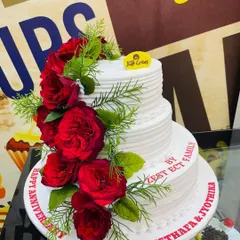 A classic 4kg three-tiered anniversary cake with simple white frosting, elegantly decorated with a cascade of fresh red roses.