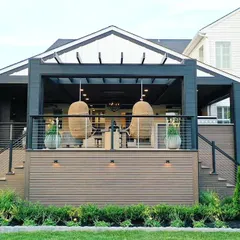 This inspirational two-story deck design showcases a modern farmhouse aesthetic. It features a covered upper lounge with hanging chairs and an open lower deck, demonstrating how we can create multi-level outdoor living spaces.