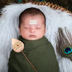 A divine little Lord Murugan. This newborn is styled with a vel and peacock feathers, a unique and spiritual theme we offer for families wanting to capture their faith.