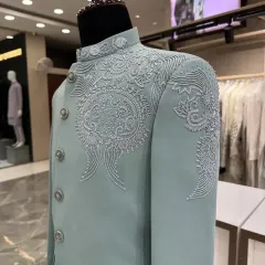 A close-up view of the intricate hand-embroidery on the mint green Jodhpuri suit.