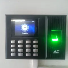 A close-up of an eSSL biometric fingerprint scanner and time attendance terminal. The green light indicates the device is active, ready to verify fingerprints for secure access or log employee check-in times.