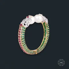 Embrace timeless beauty with our ruby, emerald, and pearl bangle. The intricate design features elephant head motifs, symbolizing strength and royalty, making it a piece of wearable art.