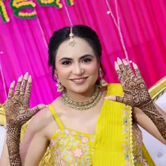 A happy bride showcasing her full mehndi design. The makeup is glowing and natural, perfect for a daytime event.
