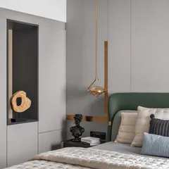 A close-up of a bedroom corner, showcasing the details. A deep green headboard is paired with grey wall paneling and gold accents. The sculptural pendant light and curated objects in the display niche reflect a sophisticated, art-forward approach to design.