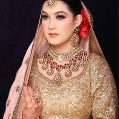 A portrait of pure grace. This look features a subtle, glowing base paired with a classic red and white kundan jewellery set against a shimmering gold lehenga. It’s a sophisticated and timeless look for any bride.
