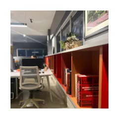 Our Pune studio, located in the leafy neighborhood of Koregaon Park. The workspace is organized around a long shelving unit in red, yellow, and blue, which houses our library of architectural books and models, reflecting our vibrant and intellectual design approach.