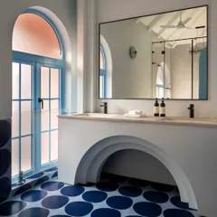 In this Goan villa bathroom, I used arches and playful circular floor tiles to create a whimsical yet sophisticated space. The frosted glass in the arched window allows for privacy while flooding the room with natural light, maintaining the home's airy, open concept.