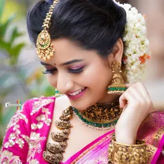 A candid, smiling portrait of Ashika Ranganath, capturing a moment of natural joy. This shot shows the beauty of traditional attire in a more relaxed pose.