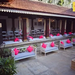 The guest seating arrangement in the courtyard of a heritage home, featuring modern benches with vibrant pink cushions that add a pop of color to the traditional setting.