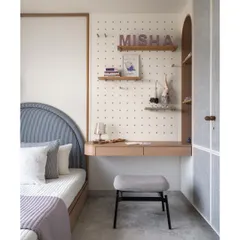 This daughter's bedroom features a charming corner platform bed and a dedicated study area with a pegboard for displaying creative projects. The design is personalized with her name, making the space truly her own.