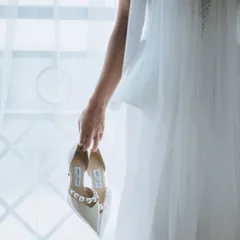 A bride holding her elegant pearl-studded heels. This artistic shot symbolizes the steps she is about to take into her new life.