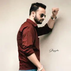 A stylish and modern individual portrait. This simple, clean shot against a plain wall is perfect for a profile picture or portfolio.