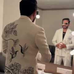 The back of this white suit features stunning black-and-white embroidery of birds and flowers, adding an element of artistry to my look.