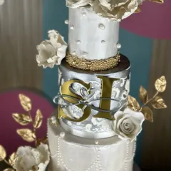 A masterpiece for a love that shines. This silver and pearl-themed wedding cake, framed by a floral hoop, combines intricate textures, delicate sugar flowers, and shimmering details for a look of timeless elegance.
