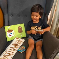 We love celebrating special moments with our families. Here, a little one proudly shows off his chocolate-themed art after enjoying his very first taste of chocolate on World Chocolate Day.