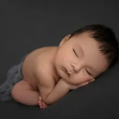 Simplicity at its finest. A newborn baby in the side lying pose on a simple, dark grey backdrop, allowing all the focus to be on their perfect form.