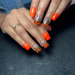 A bold and trendy set of square-shaped nails featuring a neon orange base with leopard print French tips. The gold foil accents add an extra touch of glamour.