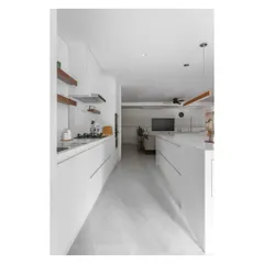 This view down the galley kitchen shows the minimalist design, with handleless white cabinets and a seamless look that extends into the living area.