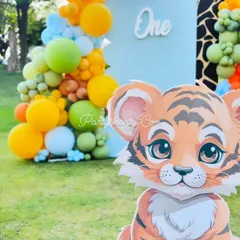 A close-up of a cute tiger cub prop for an outdoor jungle party, set against a backdrop of colorful balloons, perfect for a 'Wild One' celebration.